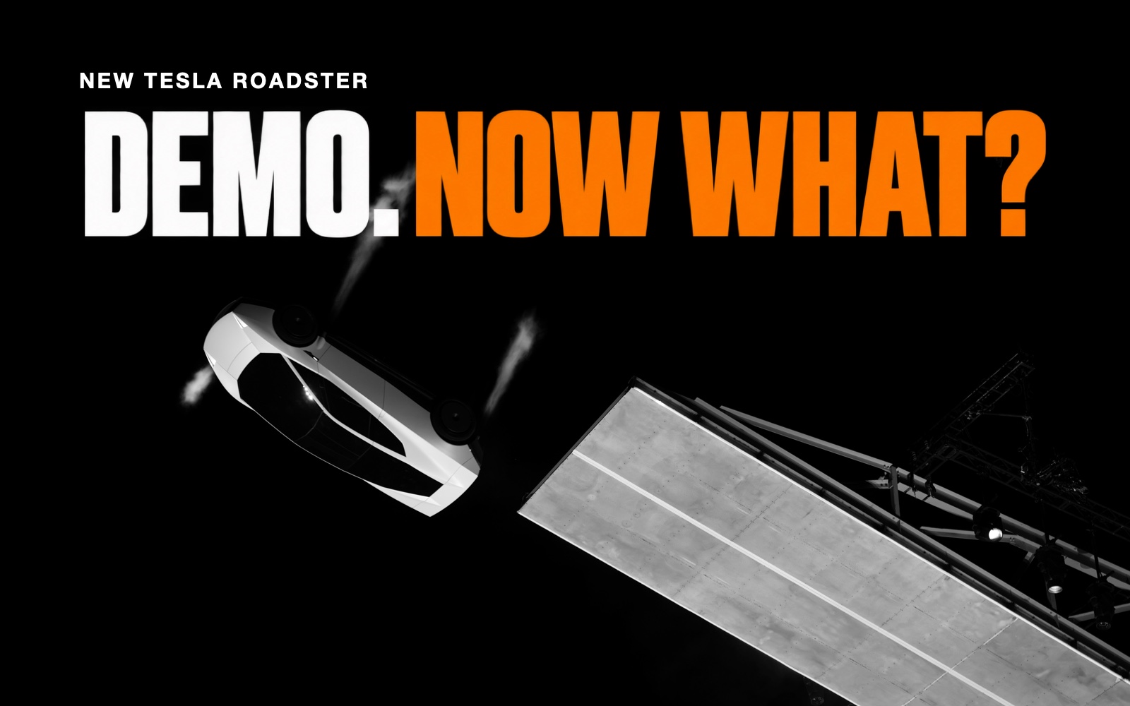 Monochrome Tesla press photograph of the white Roadster inverted beside a demonstration ramp, beneath the headline “Demo. Now what?”
