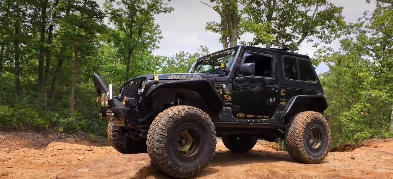 Iron Bandit, Dan's Jeep Wrangler JK, flexed out on a rock ledge in the woods